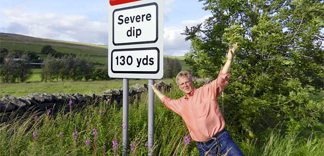 Rick Steves next to a Severe Dip road sign